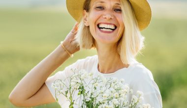 Blonde Frau voller Lebenslust auf Feld mit Blumen