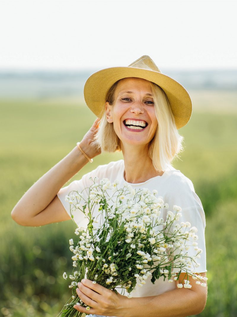 Blonde Frau voller Lebenslust auf Feld mit Blumen