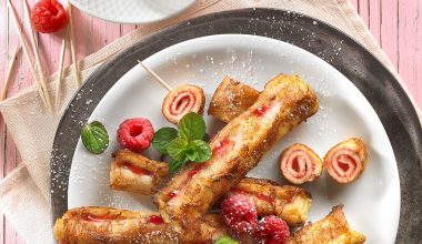 French Toast gerollt auf Teller mit Himbeeren und einer Tasse Kaffee