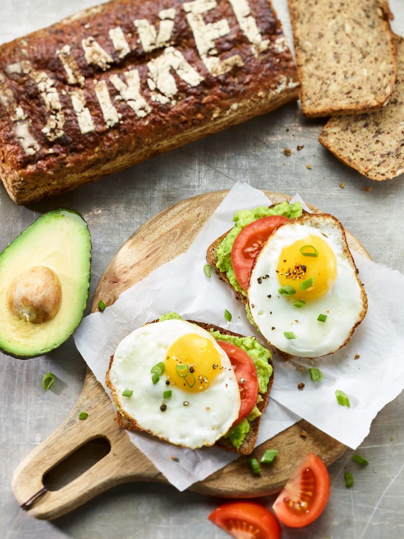 Dinkelbrot mit Avocado und Spiegelei auf Holzbrett