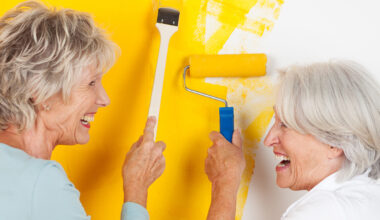 Freundinnen lachen beim Streichen der Wand