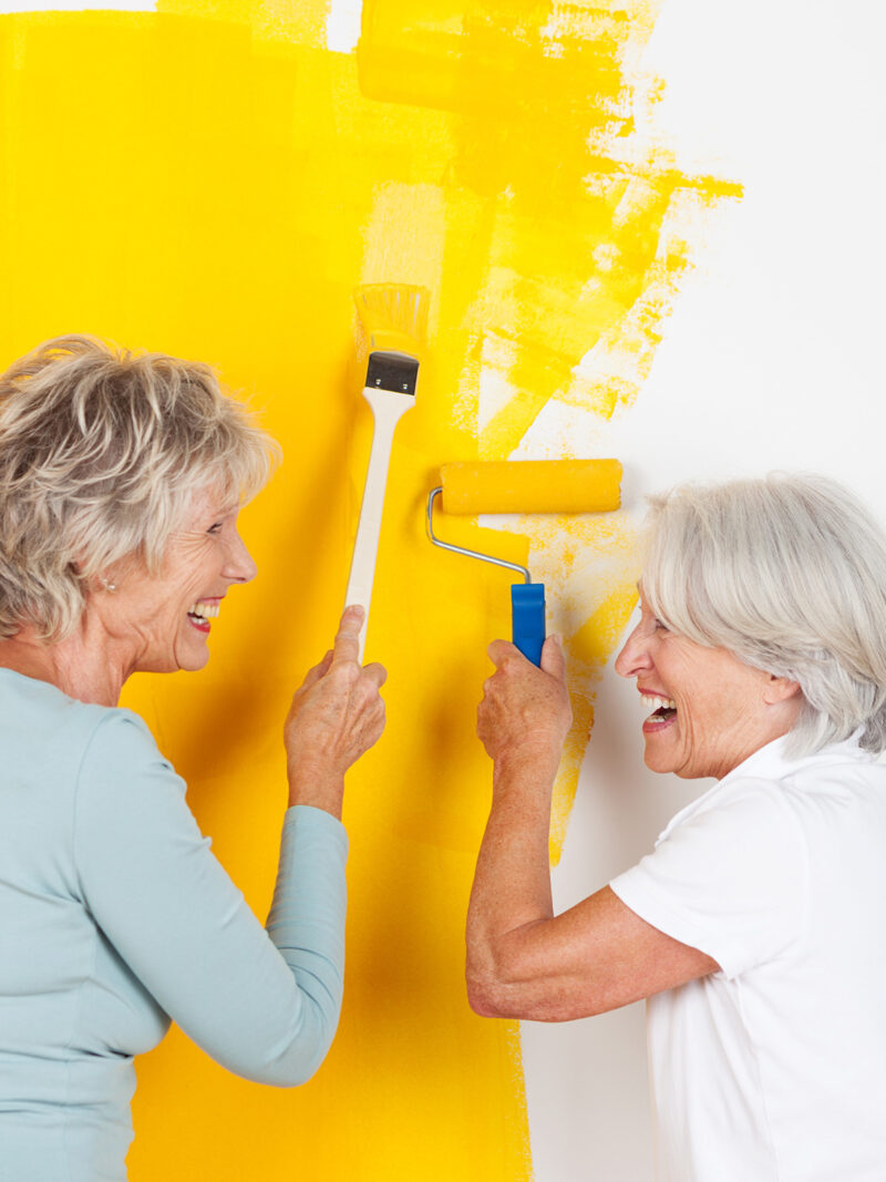 Freundinnen lachen beim Streichen der Wand