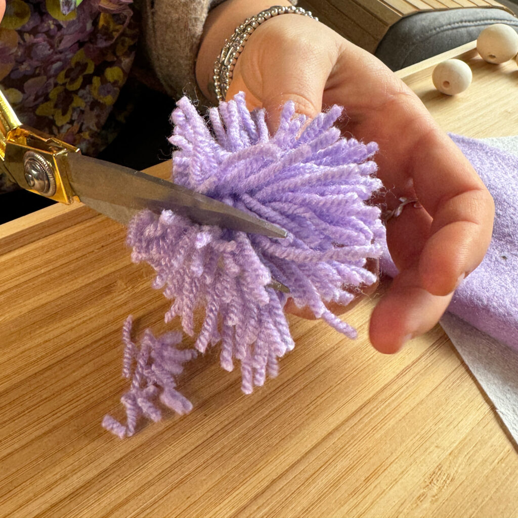 Die Wollbommel wird mit einer Schere in eine passende Form geschnitten