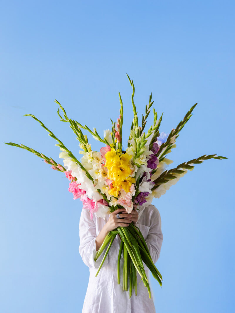 Frau mit Gladiolenstrauß im Arm