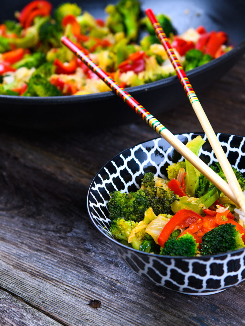 Wok mit Gemüse und Schale mit Essstäbchen