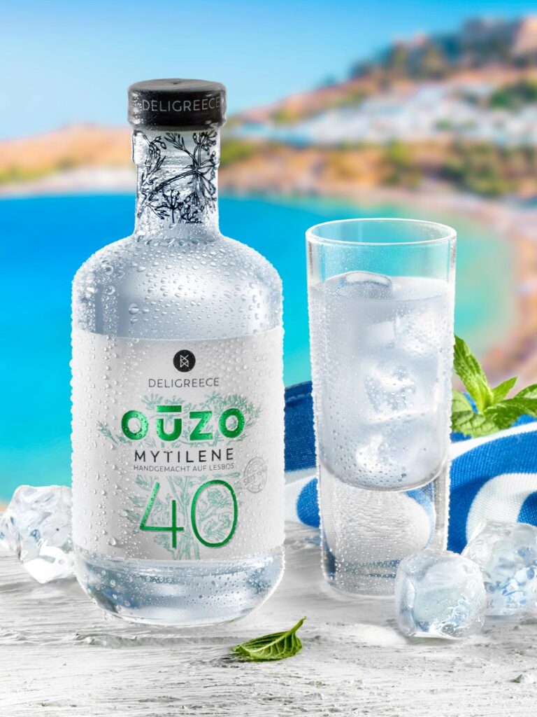 Flasche Ouzo mit Glas vor einer griechischen Bucht