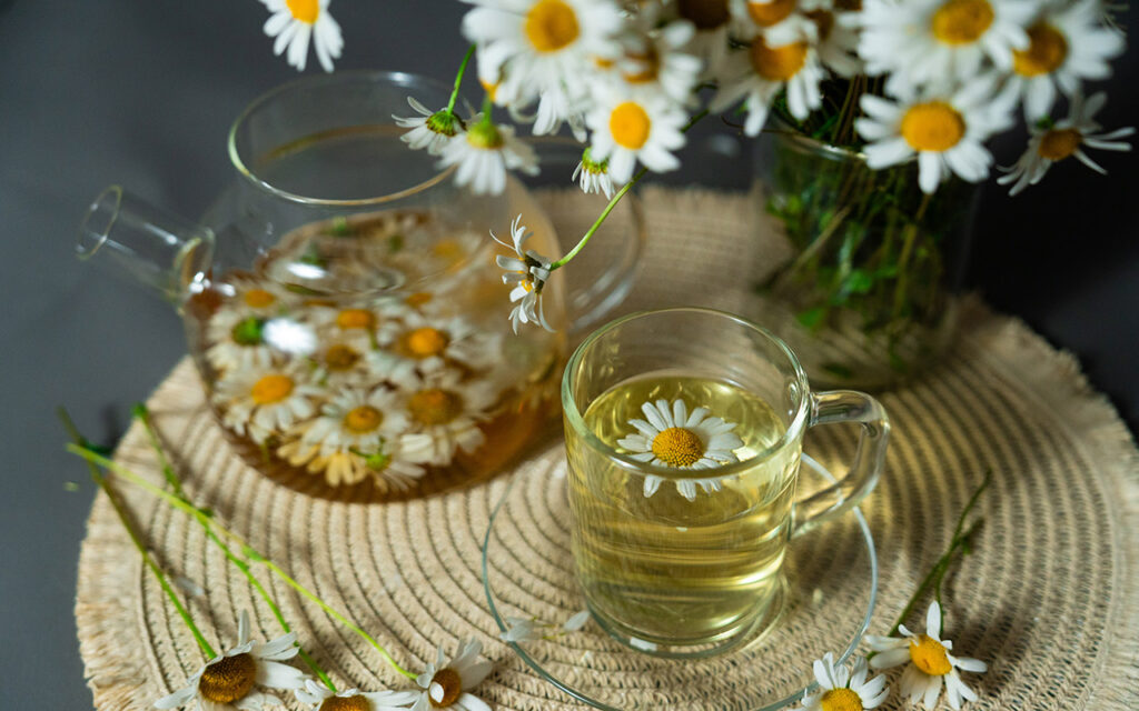 Teekanne aus Glas mit Kamillenblüten