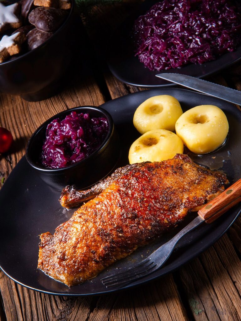 Eine halbe Bio-Ente mit knuspriger Haut auf Teller mit Rotkohl