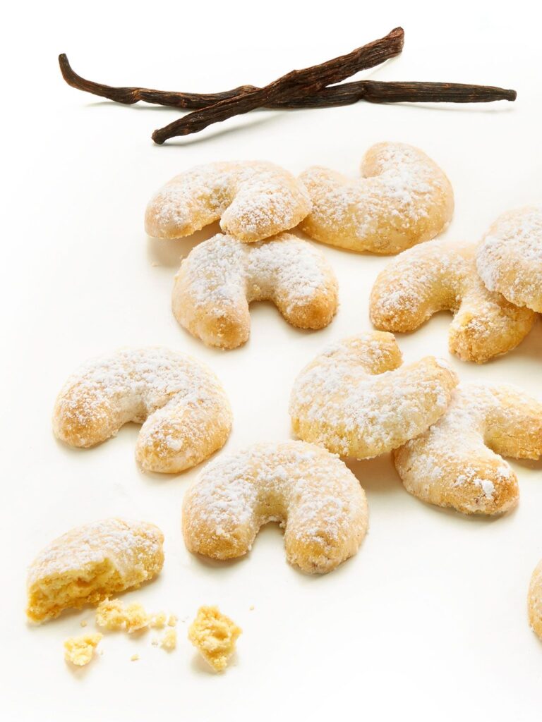 Vanillekipferl aus Österreich mit Vanilleschoten auf weißen Untergrund