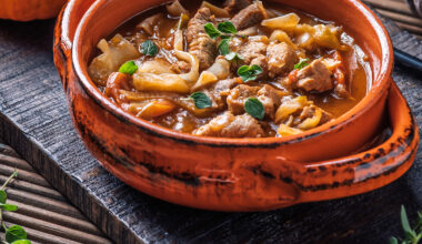 Auflaufform mit Gulasch, Kohl und Kürbis, angerichtet mit Deko und Oregano