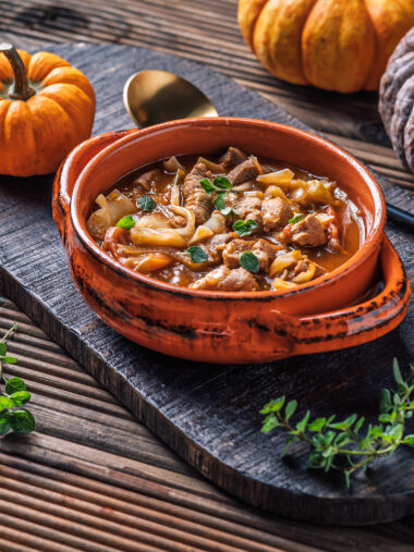 Auflaufform mit Gulasch, Kohl und Kürbis, angerichtet mit Deko und Oregano