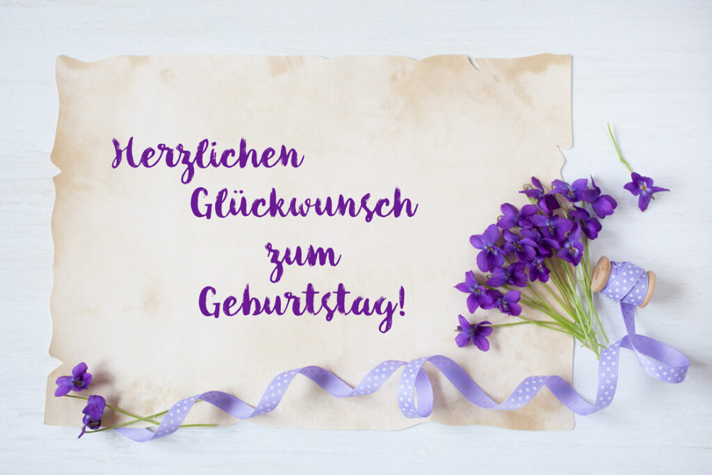 Geburtstagsglückwünsche auf altem Papier geschrieben mit Veilchenstrauß