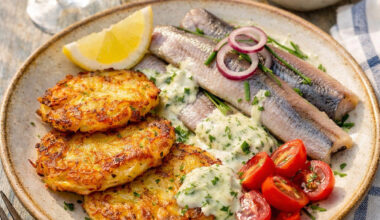 Matjes mit Röstitalern und Kräutersauce angerichtet mit etwas Tomate und Zitrone