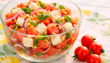 Melonen-Feta-Salat in einer Schüssel, daneben Tomaten