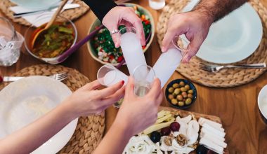 Menschen am gedeckten Tisch mit griechischen Spezialitäten