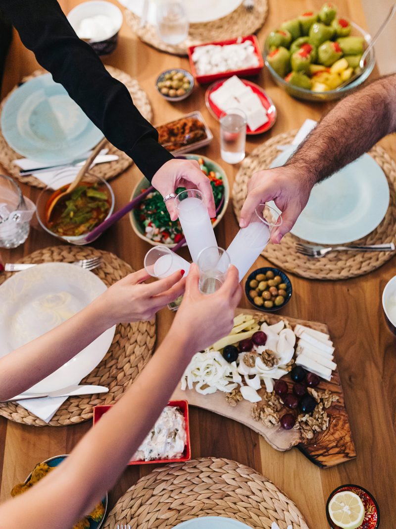 Menschen am gedeckten Tisch mit griechischen Spezialitäten