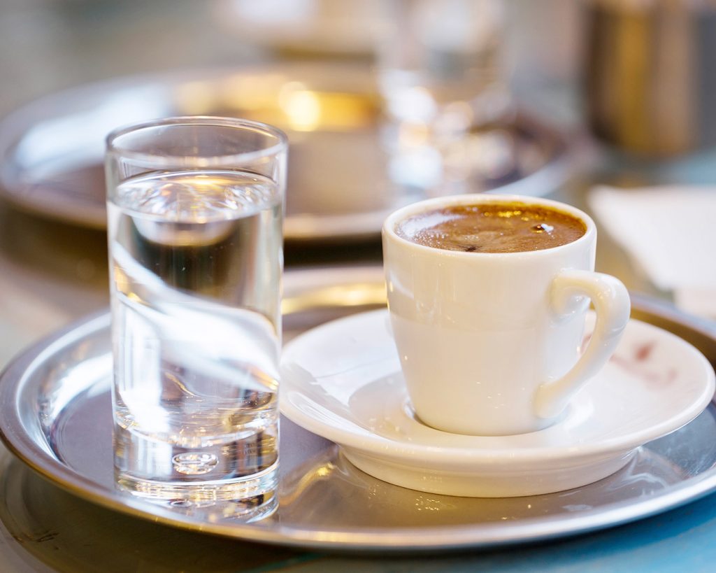 Ein Glas mit Wasser und eine Tasse Kaffee