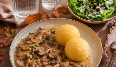Teller mit Pilzgulasch und Klößen angerichtet auf einem herbstlichen Tisch