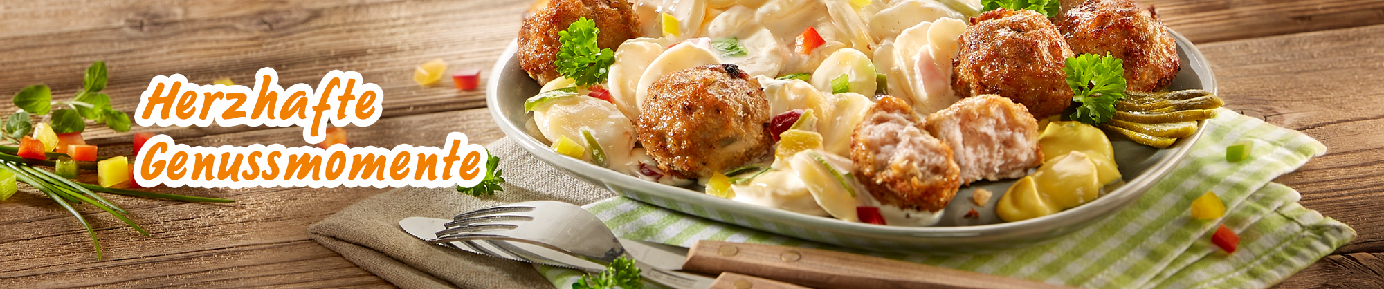 Klopse mit cremigem Kartoffelsalat, Gurken und Petersilie auf gedecktem Tisch