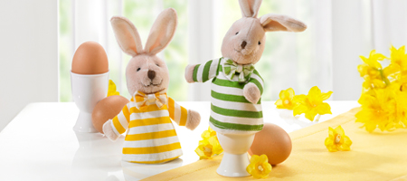 Niedliche Hasen-Eierwärmer in Shirts mit Ostereiern und Frühlingsdeko.