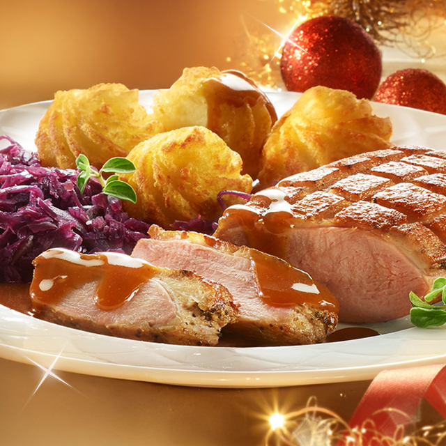 Festtagsgericht mit Entenbrust, Rotkohl und Kroketten auf weihnachtlicher Tafel