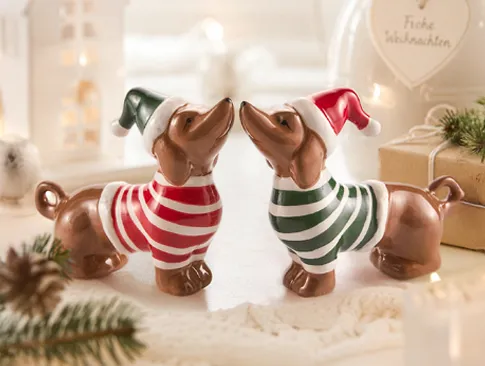 Zwei weihnachtliche Dekofiguren auf festlich dekoriertem Tisch