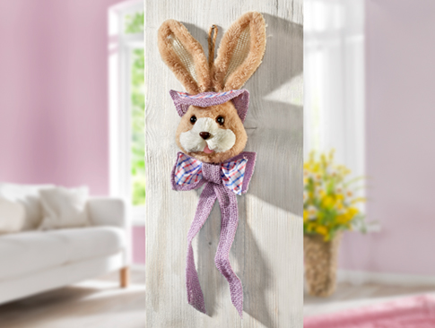Deko-Hase mit Schleife an heller Wand in Wohnzimmer