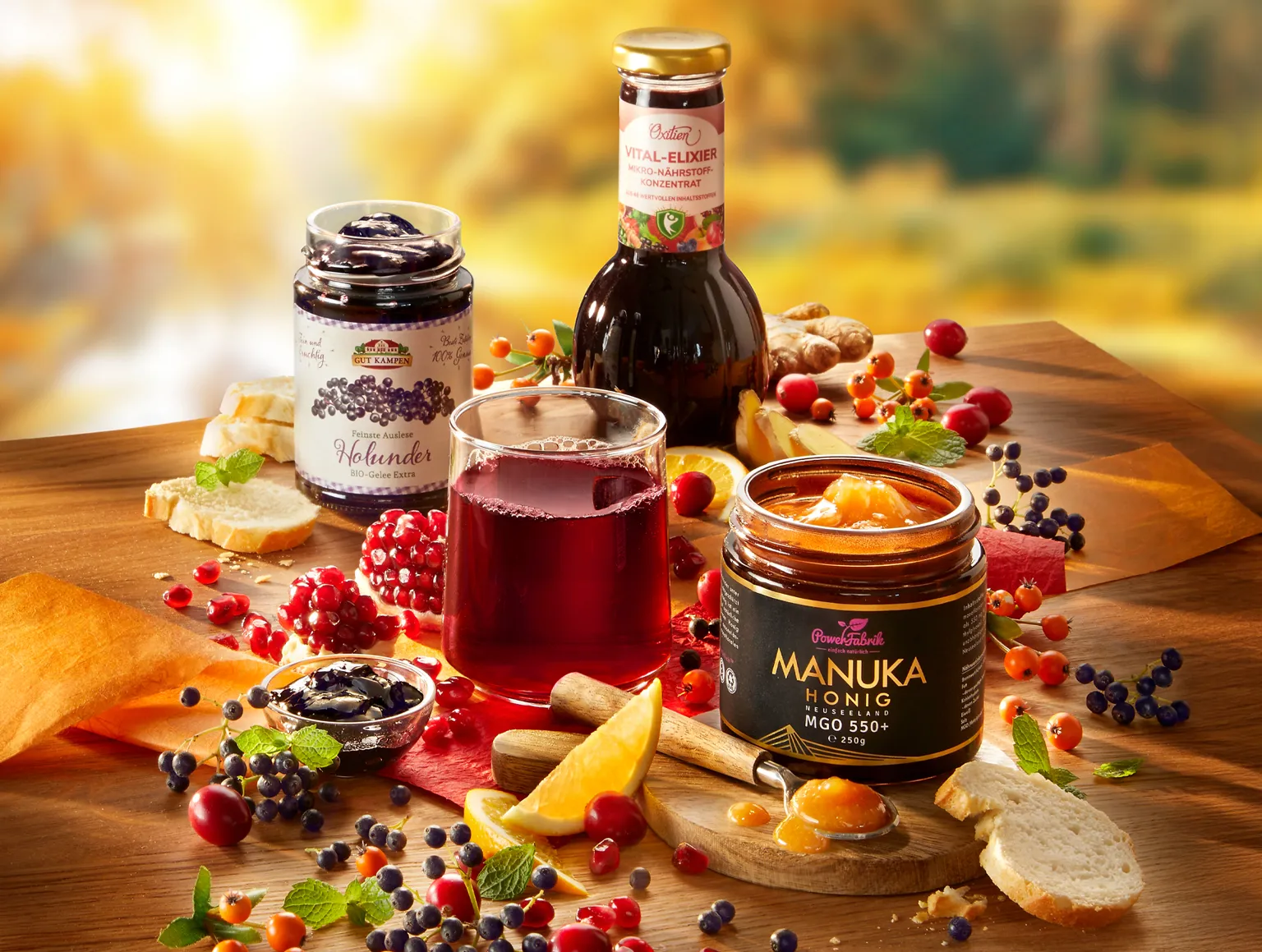 Honig, Holundergelee und Saft mit Früchten auf herbstlich gedecktem Tisch