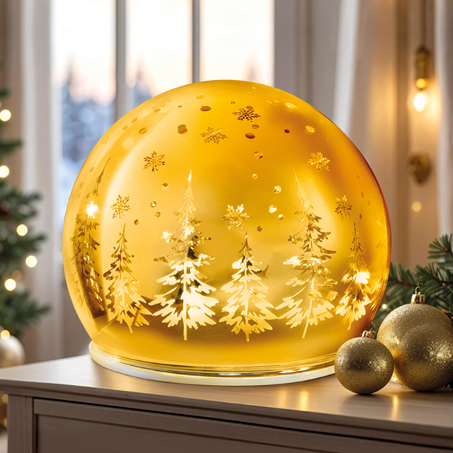 Goldene LED-Glaskugel mit Winterwald-Motiv vor weihnachtlicher Kulisse