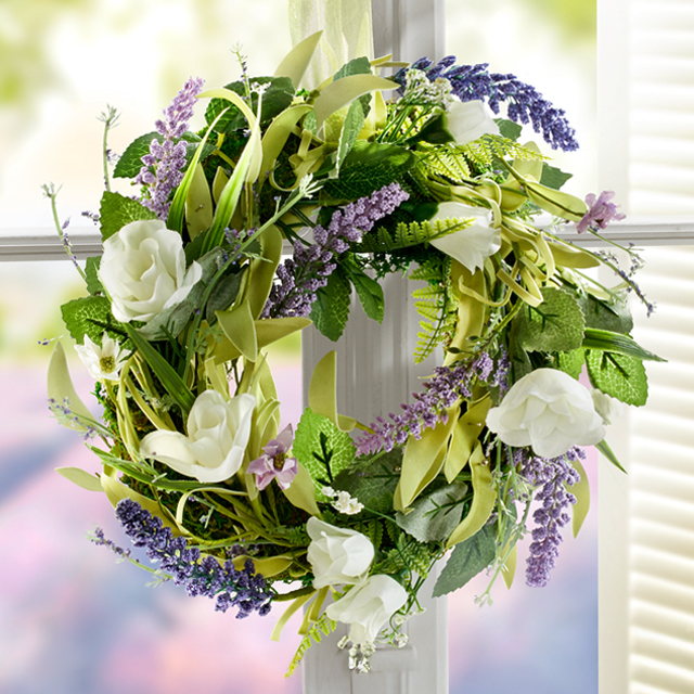 Türkranz mit weißen und lila Kunstblumen am Fenster
