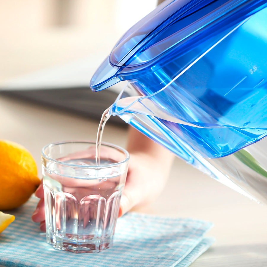 Gefiltertes Wasser wird aus Kanne in ein Glas eingeschenkt