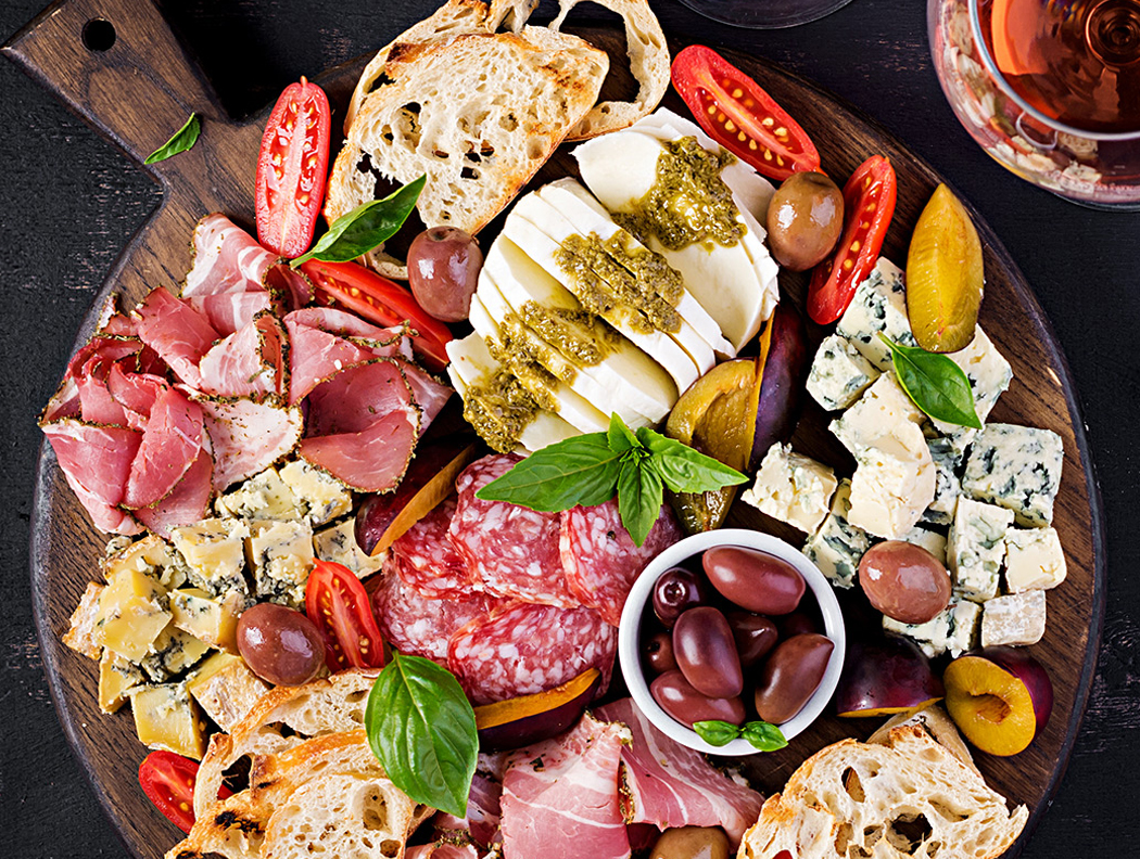 Spanischer Vorspeisenteller mit Käse, Wurst, Brot, Oliven, Tomaten und Basilikum