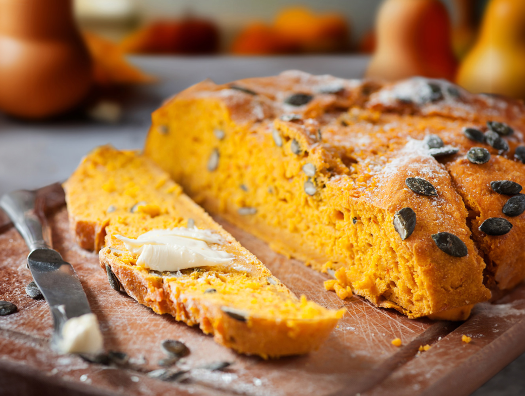 Frisches Butternuss-Kürbis-Brot mit Kürbiskernen, mit Butter auf Holzbrett