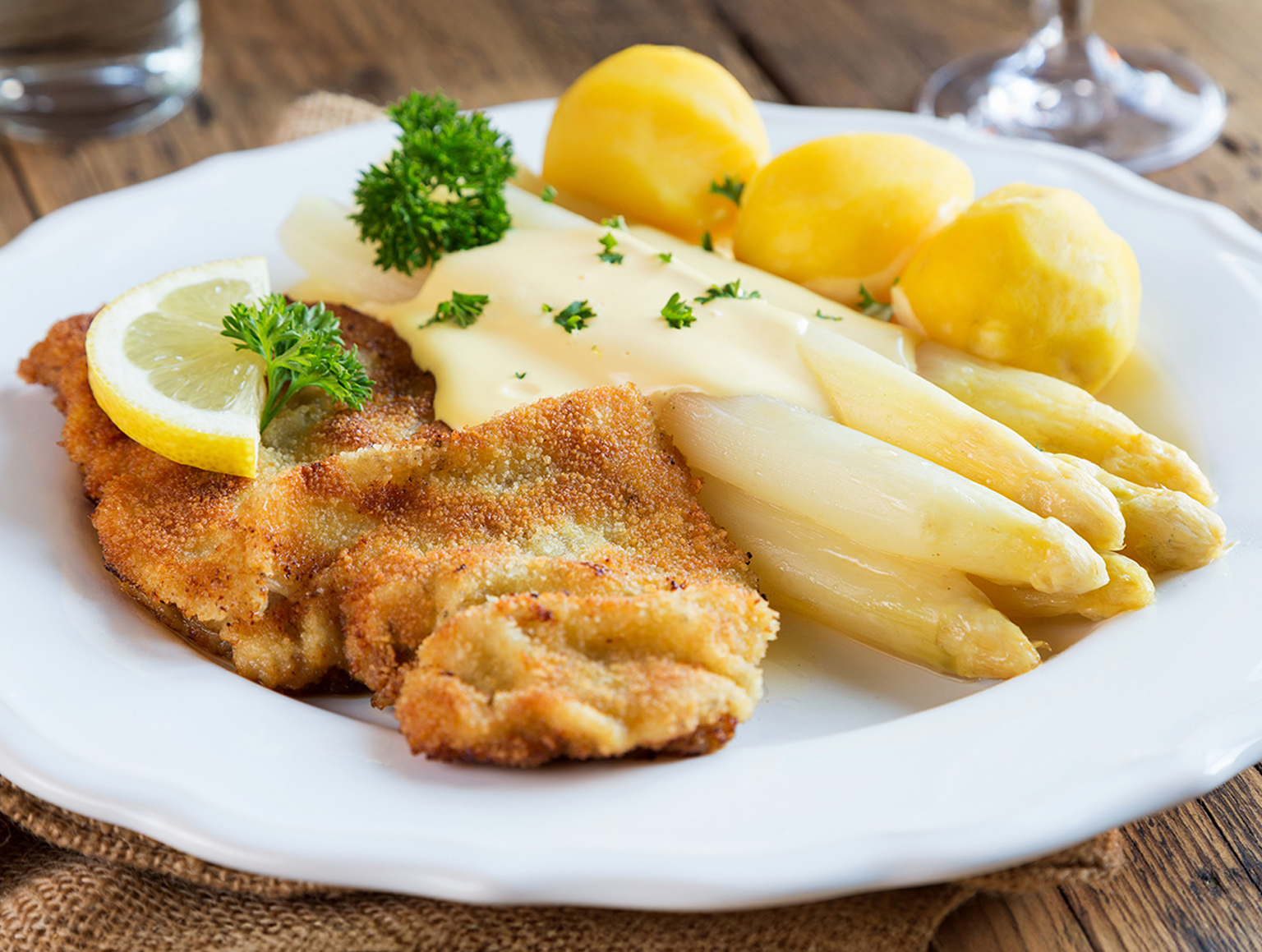 Spargel mit Sauce Hollandaise, Schnitzel und Kartoffeln auf weißem Teller