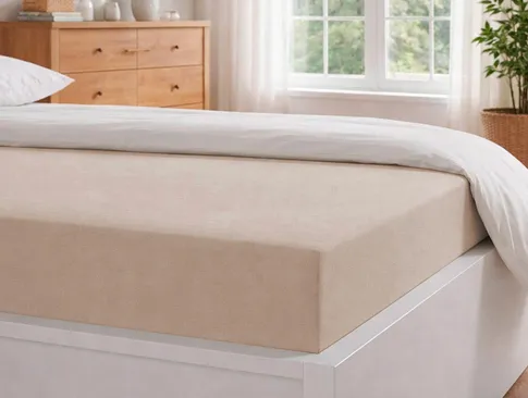 Beiges Spannbettlaken auf einem hellen Bett in gemütlichem Schlafzimmer