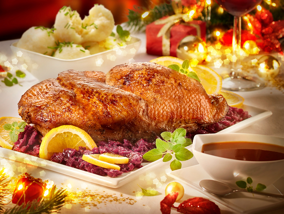 Festtagsgericht mit Entenbrust, Rotkohl und Kroketten auf weihnachtlicher Tafel