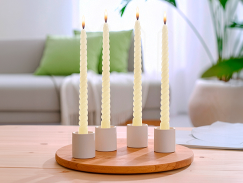 Vier gedrehte Stabkerzen auf Holztablett als Osterdeko