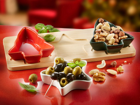Weihnachtliche Schälchen in Sternform mit Oliven und Nüssen auf Holztablett als festliche Tischdeko