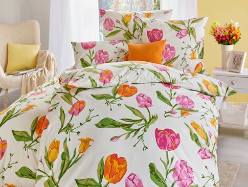 Bettwäsche mit buntem Tulpenmuster in gemütlichem Schlafzimmer.