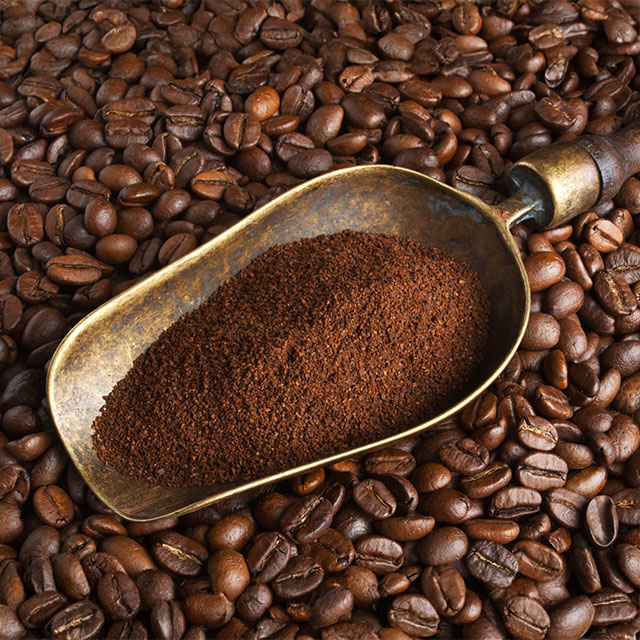 Gemahlener Kaffee in Metallschaufel auf Kaffeebohnen