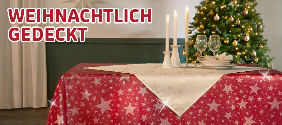 Weihnachtlich gedeckter Tisch mit roter Sternen-Tischdecke und Kerzen