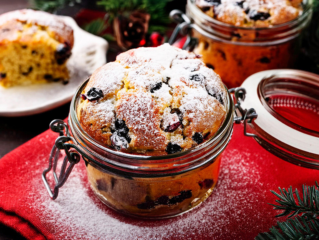Mini-Stollen im Glas mit Puderzucker, auf rotem Tuch weihnachtlich dekoriert