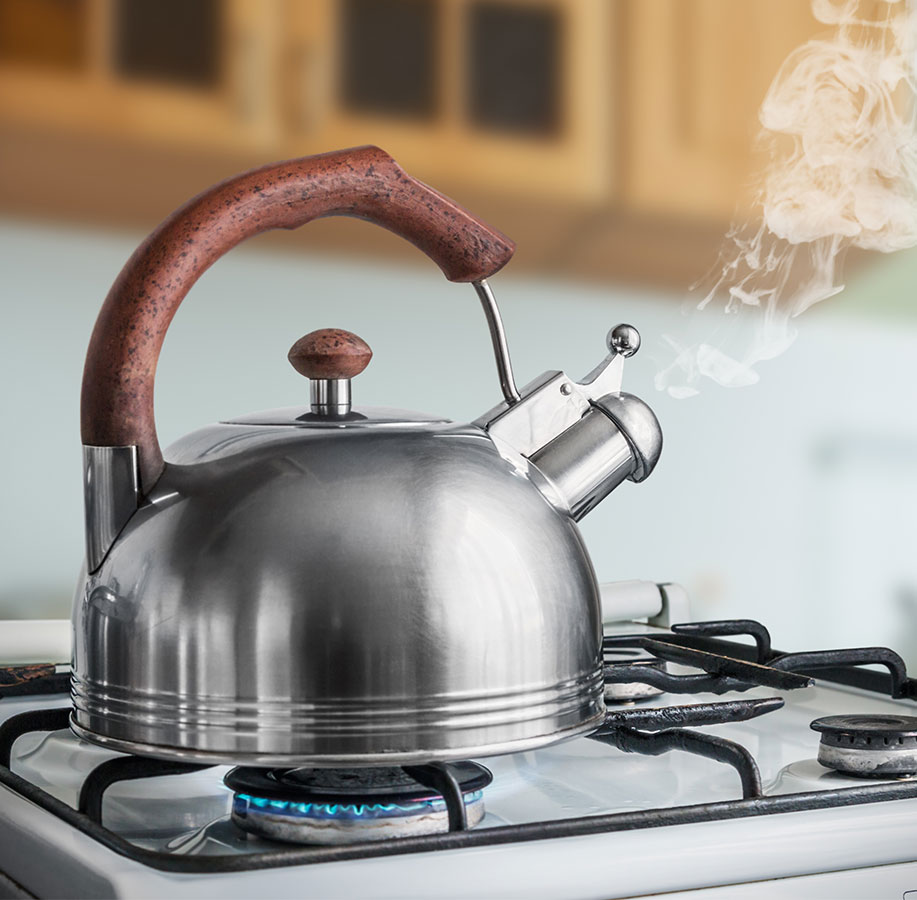 Wasserkessel kocht auf Gasherd und gibt Dampf ab